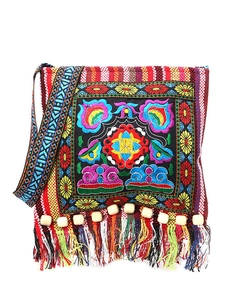 Detail of bohemian crossbody bag featuring colorful floral embroidery and beaded tassels