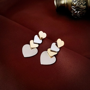 Detailed view of heart-shaped layered earrings with gold and silver metallic finish