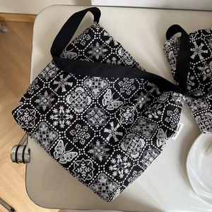 Close-up of exquisite white butterfly embroidery on black canvas underarm bag