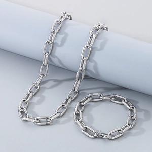 Detail of silver textured paperclip chain necklace and bracelet set on a blue podium