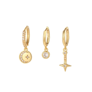 Detailed macro view of three gold-plated huggie hoop earrings with star and moon charms