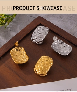 Detail of gold and silver matelassé geometric stud earrings on a dark wood tray