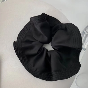 Detailed view of black satin oversized scrunchie with rich pleated folds and silk texture