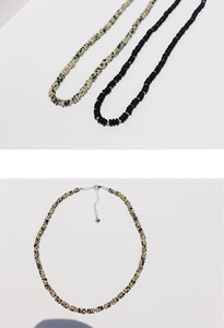 Detailed macro view of black agate and spotted stone beaded necklace with silver clasp