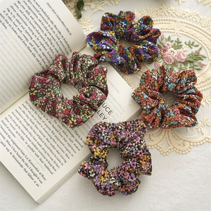 Detailed close-up of four floral print scrunchies in vintage blue, green, and orange colors