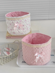 Close-up of quilted floral and striped storage baskets with lace trim and pink bows