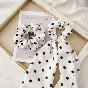 Macro detail of polka dot fabric scrunchies with long ribbons on artistic background