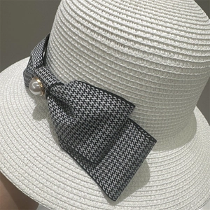 Close-up of a woven straw hat featuring a bow and pearl detail for women