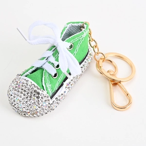 Detail eines grünen Turnschuh-Schlüsselanhängers mit Strasssteinen und goldenem Ring