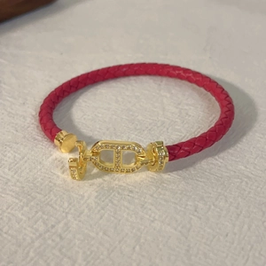 Dettaglio del bracciale in pelle rossa intrecciata con fibbia CD dorata e cristalli