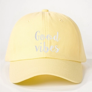 Detail of Good Vibes white embroidery on a yellow cotton canvas baseball cap
