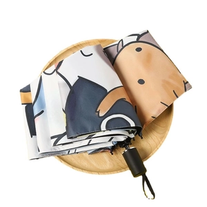 Folded cat pattern sun umbrella in a wooden tray with a black handle and white fabric