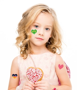 Close-up of colorful heart temporary tattoos on child's face and arm for Valentine's Day