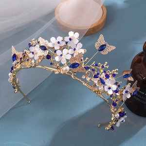 Close-up of golden bridal crown with blue rhinestones, white flowers, and butterflies