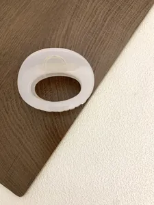 Detail of a translucent milky white oval hair claw clip with a minimalist hollow design