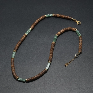 Detail of brown coconut wood beads and green stones with golden lobster clasp and chain