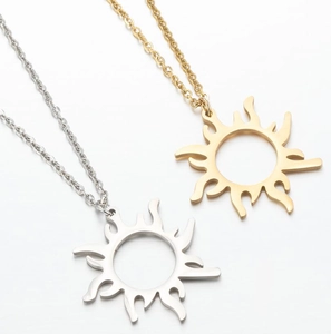 Detailed macro of gold and silver sunburst pendant necklaces on a clean white surface