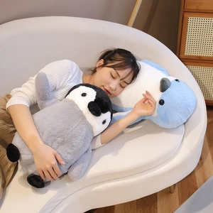 Girl sleeping peacefully holding soft grey and blue penguin plush stuffed animals