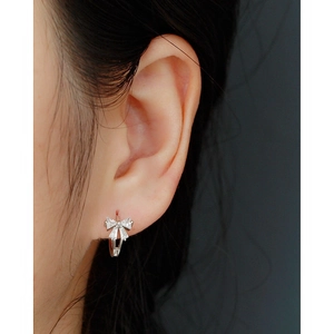 Close-up of elegant silver bow stud earring with zircons on a model ear lobe