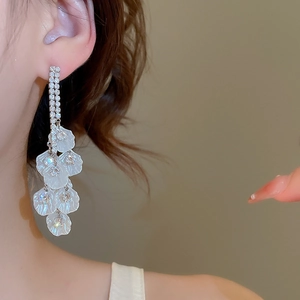 Détail macro de boucles d'oreilles à longs pompons avec pétales blancs et cristaux brillants