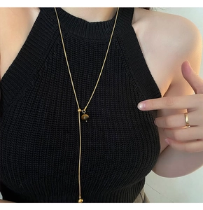 Vue détaillée du long collier en acier titane doré avec pendentif en œil de tigre