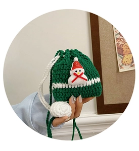 Detail of dark green handmade crochet Christmas pouch with white stripes and snowman doll