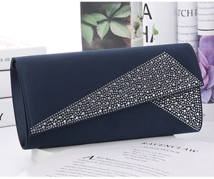 Detail of navy blue satin evening clutch bag with sparkling rhinestone decoration on books