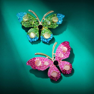 Exquisite rhinestone butterfly brooches in gradient blue and purple on green background