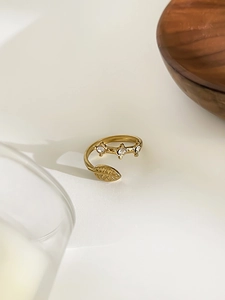 Detailed view of adjustable gold-tone leaf ring with three clear sparkling zircons