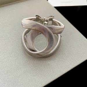Vue rapprochée d'un bracelet en métal argenté avec texture spirale torsadée sur papier gris