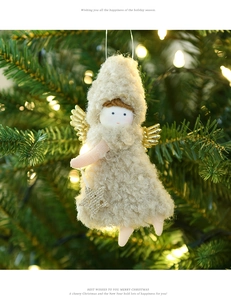 Detail of plush Christmas angel ornament with gold wings on a glowing holiday tree