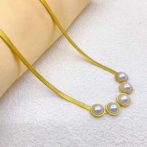 Elegant gold snake chain necklace with five round white pearls on a textured background