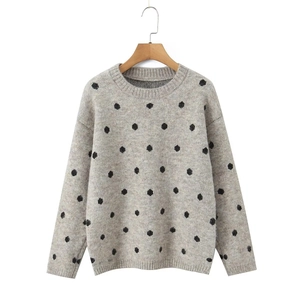 Dettaglio di un maglione grigio a maglia con pois neri e scollo a costine rifinito