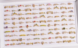 Overhead display of varied golden zircon rings with colorful gemstones in a jewelry organizer