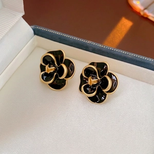 Vintage black enamel camellia flower stud earrings with gold trim on jewelry box