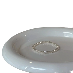 Elegant pearl bracelet with square-cut zircon pendant on a white ceramic tray