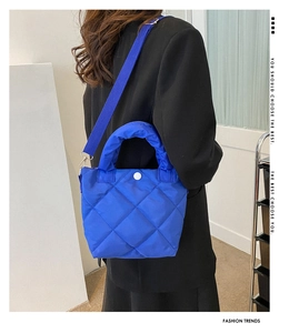 Close-up of blue quilted bucket bag showing matte nylon texture and wide strap