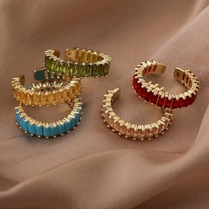 Minimalist gold open rings with colorful square zircons on elegant beige silk fabric