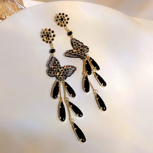 Detailed macro view of black mesh butterfly earrings with gold tassels and crystals