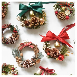 Flat lay of handmade Christmas wreaths featuring pine cones, gold bells and red ribbons