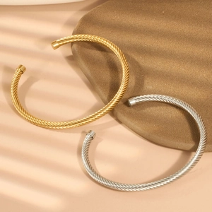 Makro-Detail von gedrehten Seil-Armreifen in Gold und Silber mit Schatten-Lichteffekten