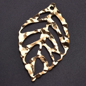 Macro view of gold leaf pendant with hammered texture and hollow leaf vein pattern