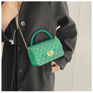 Detail of green transparent jelly bag with quilted pattern, pearl handle and gold chain strap