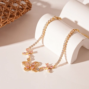 Close-up of golden tennis chain necklace featuring pink zircon butterfly pendants