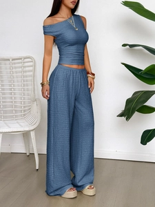 Detail of blue two-piece set featuring textured off-shoulder top and high-waist wide-leg pants