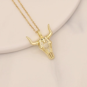 Detail of a gold bull head pendant with micro-inlaid zircons on a beige tray