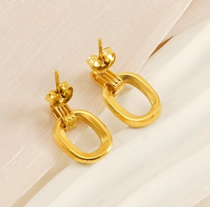 Close-up of golden oval double-loop earrings on a textured minimalist background