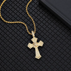 Macro shot of gold hip hop cross pendant with paved zircons on twisted rope chain