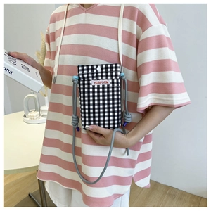 Close-up of black and white checkered crossbody phone bag with button and rope strap