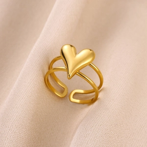 Close-up of golden heart ring with double-layer band on a soft white satin surface
